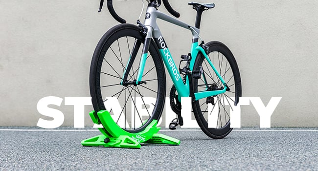 Road bicycle with teal frame and white accents, positioned on a bright green bike stand. Large 'STEADY' text overlaid on the image.