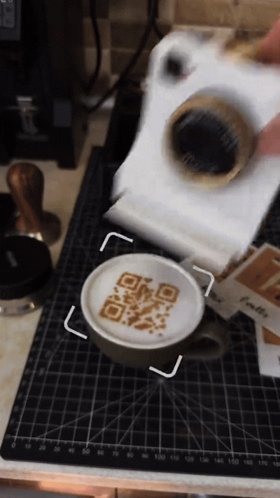Latte art camera pressing powder onto coffee foam